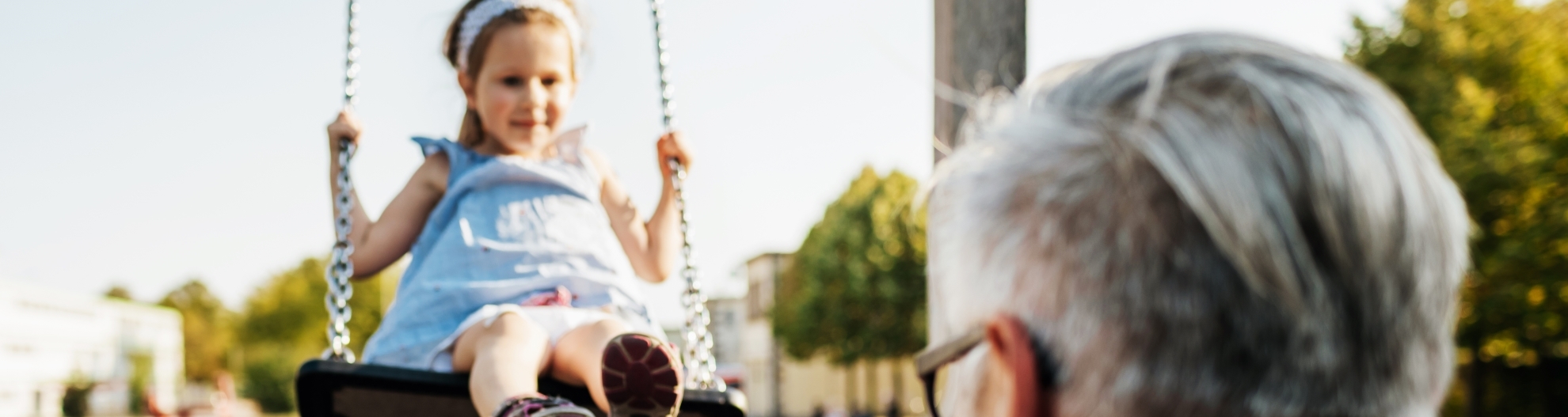 Grandpa Pushing His Granddaughter On Swing Set